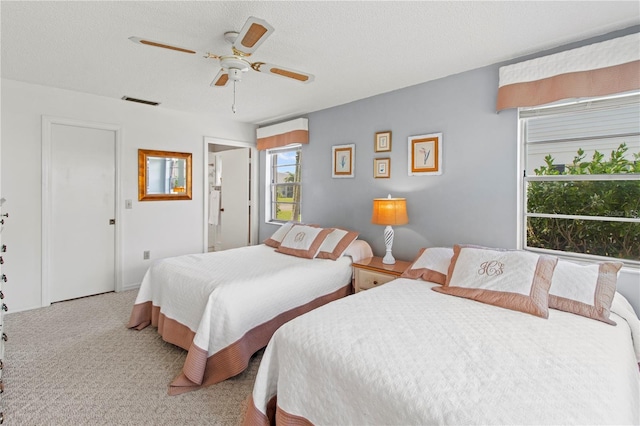 bedroom with carpet flooring, a ceiling fan, visible vents, and a textured ceiling