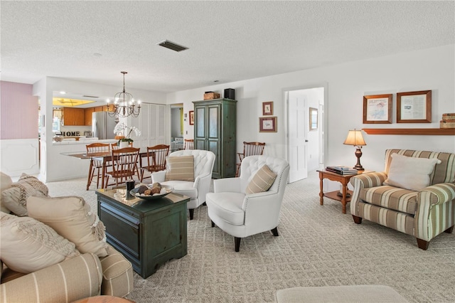 living room featuring a textured ceiling, light colored carpet, visible vents, and a chandelier