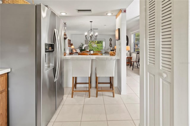 kitchen with light tile patterned floors, visible vents, stainless steel fridge with ice dispenser, decorative light fixtures, and a notable chandelier