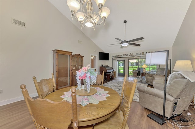 dining room featuring high vaulted ceiling, ceiling fan with notable chandelier, and light wood-type flooring