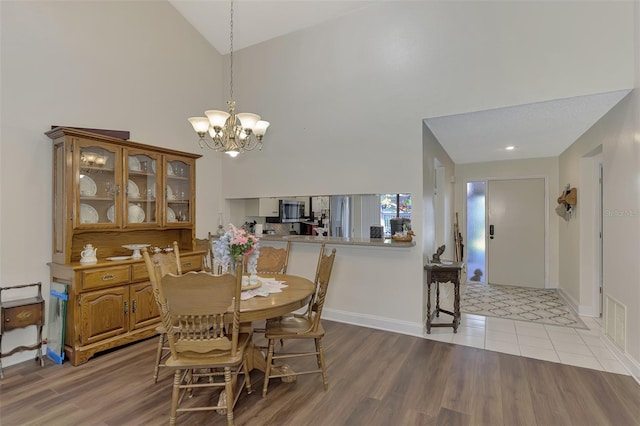 dining room featuring high vaulted ceiling, light hardwood / wood-style flooring, and a notable chandelier