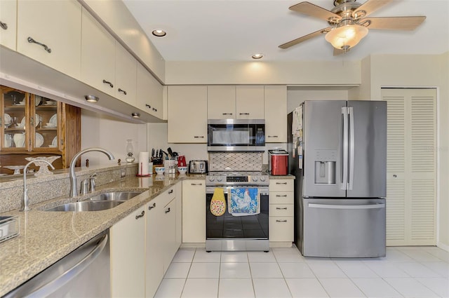 kitchen with cream cabinets, appliances with stainless steel finishes, tasteful backsplash, sink, and ceiling fan