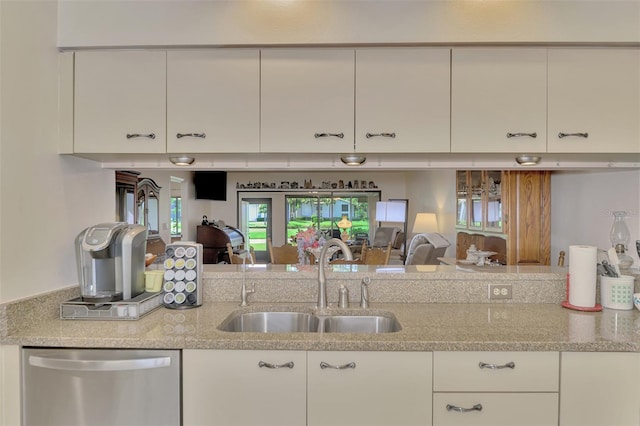 kitchen featuring white cabinetry, light stone counters, stainless steel dishwasher, and sink