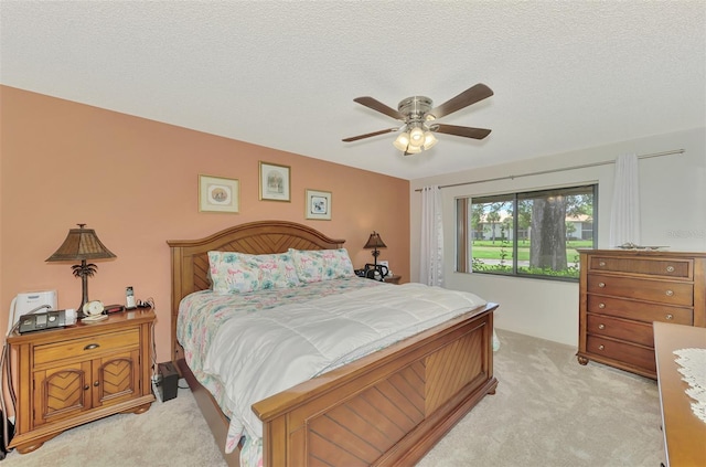 bedroom featuring light colored carpet, ceiling fan, and a textured ceiling