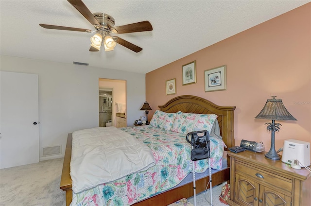 bedroom with light colored carpet, connected bathroom, ceiling fan, and a textured ceiling