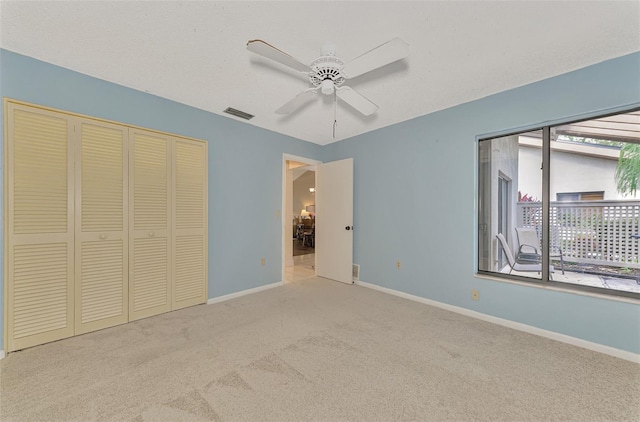 unfurnished bedroom featuring multiple windows, ceiling fan, light colored carpet, and a closet