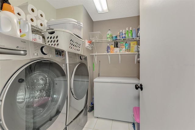 washroom with a textured ceiling, independent washer and dryer, and light tile patterned flooring