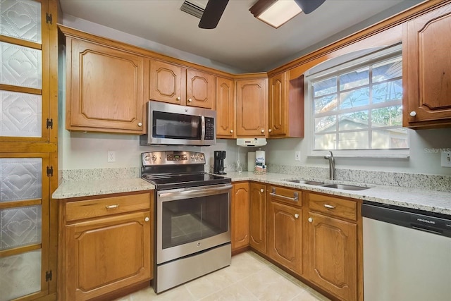 kitchen with appliances with stainless steel finishes, light stone counters, sink, and ceiling fan