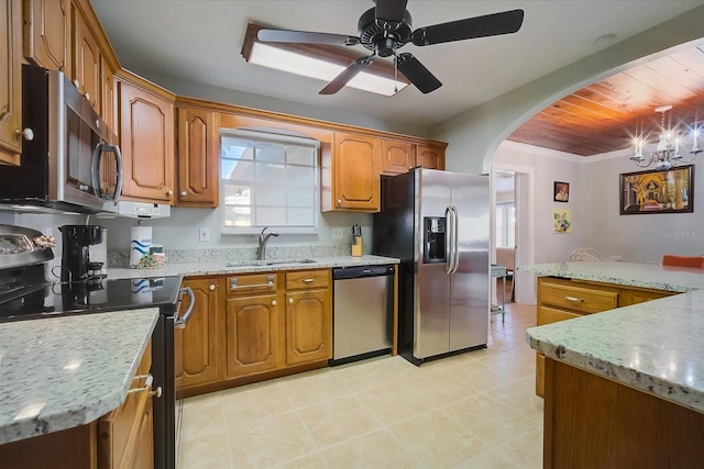 kitchen with ceiling fan with notable chandelier, appliances with stainless steel finishes, wood ceiling, light stone counters, and sink