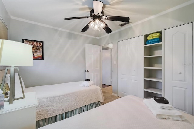 bedroom with ceiling fan, crown molding, and multiple closets