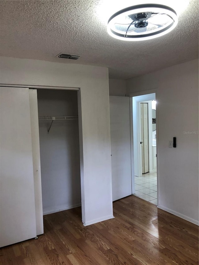 unfurnished bedroom featuring a closet, dark hardwood / wood-style floors, and a textured ceiling