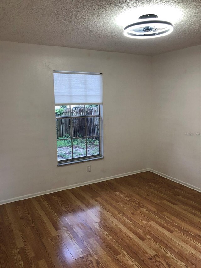 empty room with a textured ceiling and dark wood-type flooring