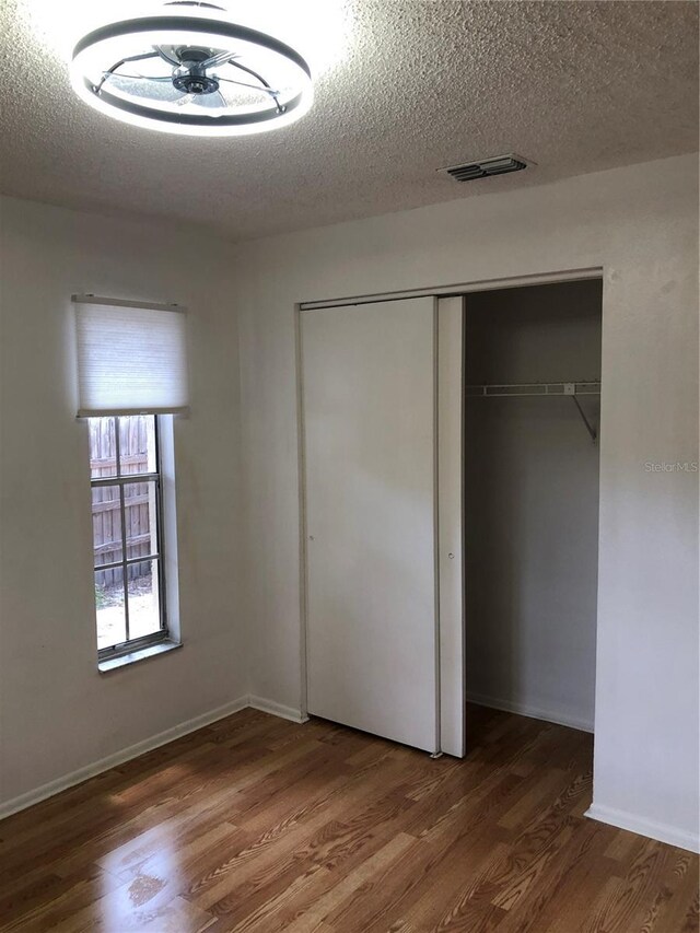 unfurnished bedroom featuring a closet, dark hardwood / wood-style flooring, and a textured ceiling