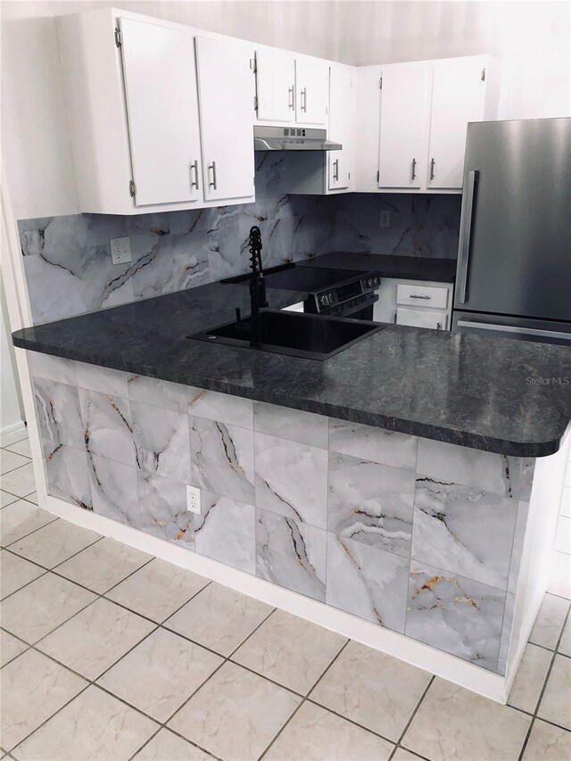 kitchen with white cabinets, dark stone countertops, sink, kitchen peninsula, and tasteful backsplash