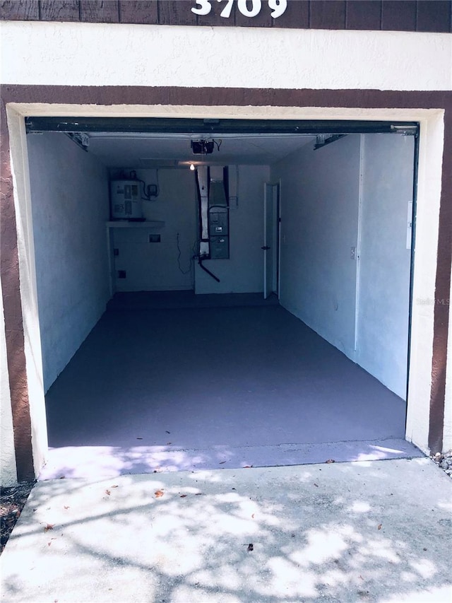 garage featuring electric panel, a carport, and heating unit