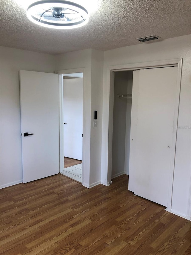 unfurnished bedroom featuring a textured ceiling and dark hardwood / wood-style flooring