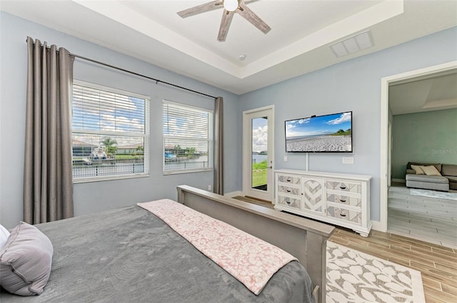 bedroom with a tray ceiling, ceiling fan, and light hardwood / wood-style floors