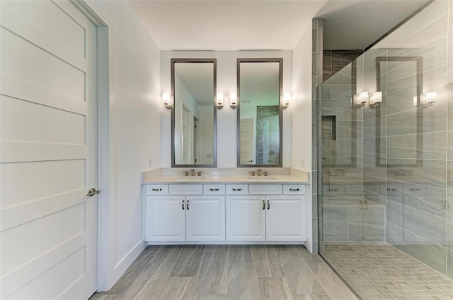 bathroom with a tile shower, a textured ceiling, and vanity