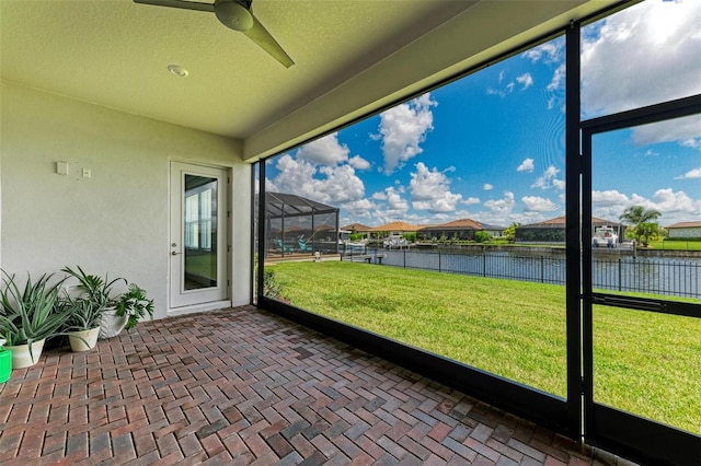 unfurnished sunroom with a water view and ceiling fan