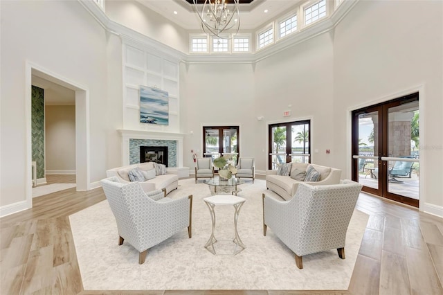 living room with a chandelier, a high ceiling, light wood-type flooring, and french doors