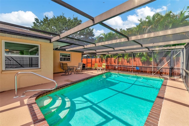 view of pool with glass enclosure and a patio