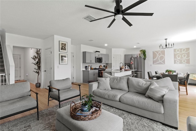 living room with ceiling fan, sink, a textured ceiling, and light hardwood / wood-style flooring