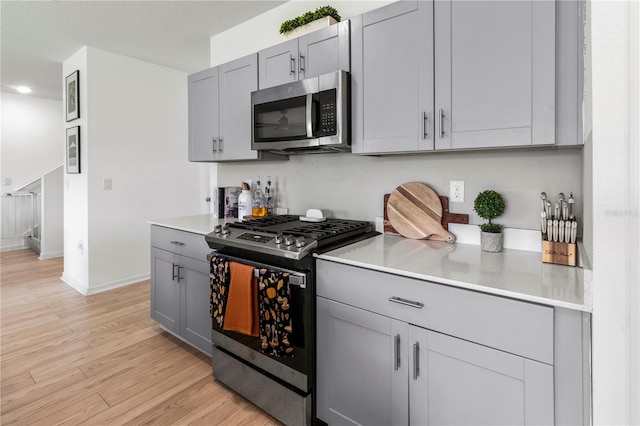 kitchen with gray cabinets, stainless steel appliances, and light hardwood / wood-style floors