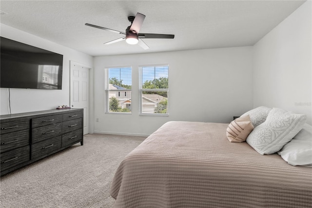 bedroom with a textured ceiling, ceiling fan, and light carpet