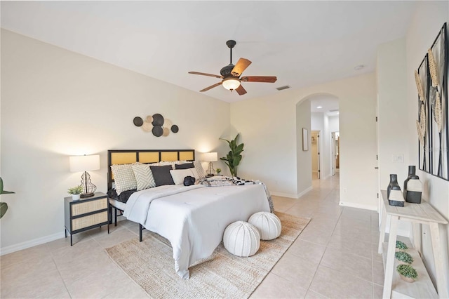 bedroom featuring arched walkways, light tile patterned floors, and baseboards