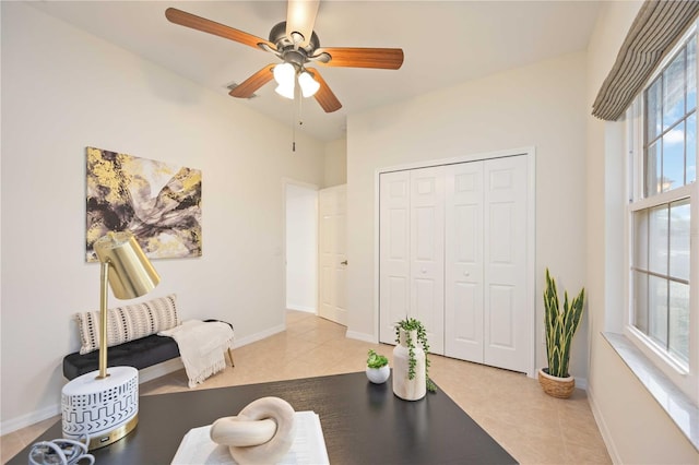 interior space with baseboards, a ceiling fan, and tile patterned floors