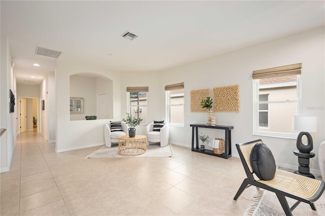 sitting room featuring arched walkways, visible vents, and baseboards