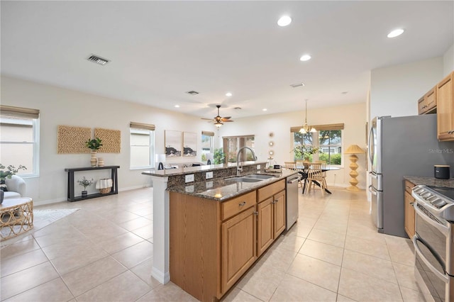 kitchen featuring light tile patterned floors, visible vents, appliances with stainless steel finishes, a sink, and dark stone counters