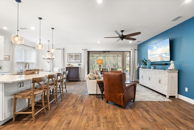 living room with dark hardwood / wood-style flooring, sink, and ceiling fan with notable chandelier