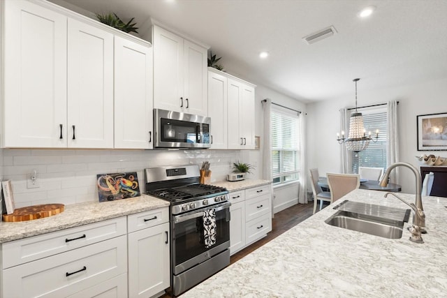 kitchen featuring stainless steel appliances, pendant lighting, white cabinetry, and sink