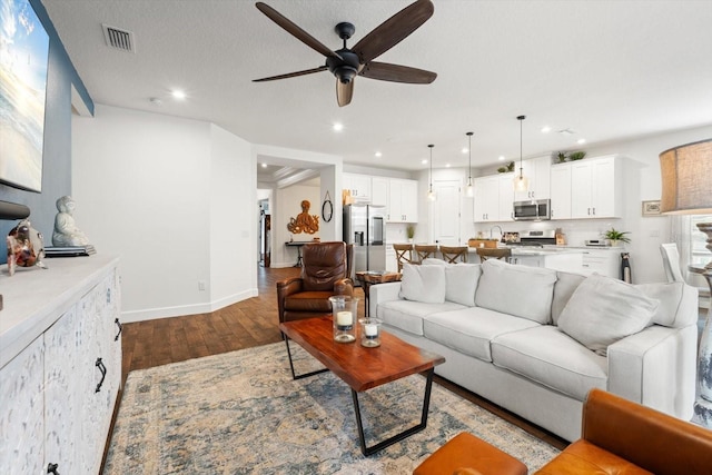 living room featuring ceiling fan, sink, a textured ceiling, and hardwood / wood-style flooring