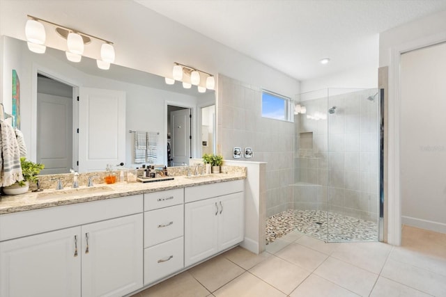 bathroom with vanity, a tile shower, and tile patterned flooring