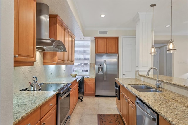 kitchen with light stone counters, pendant lighting, stainless steel appliances, sink, and wall chimney range hood