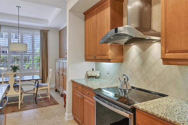 kitchen with decorative backsplash, wall chimney exhaust hood, light stone countertops, and stainless steel range with electric cooktop