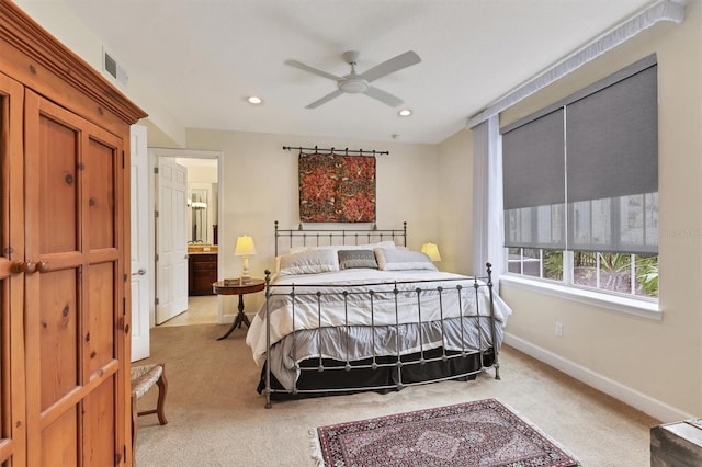 bedroom featuring light carpet, ceiling fan, and ensuite bathroom