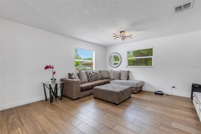 living room featuring a chandelier, light hardwood / wood-style floors, and a textured ceiling