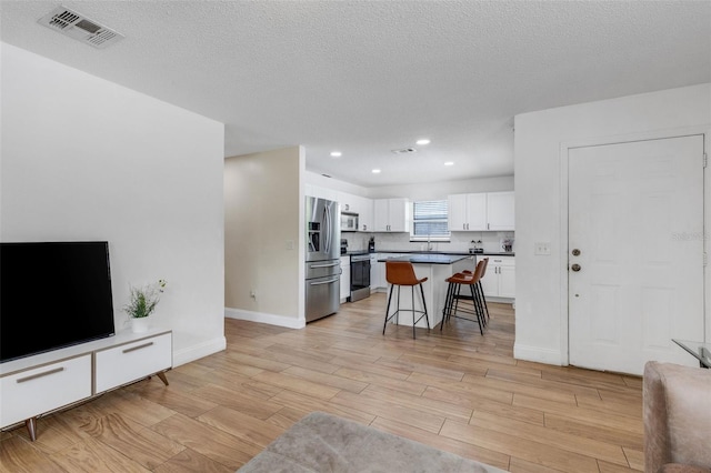 living room featuring a textured ceiling, light hardwood / wood-style flooring, and sink