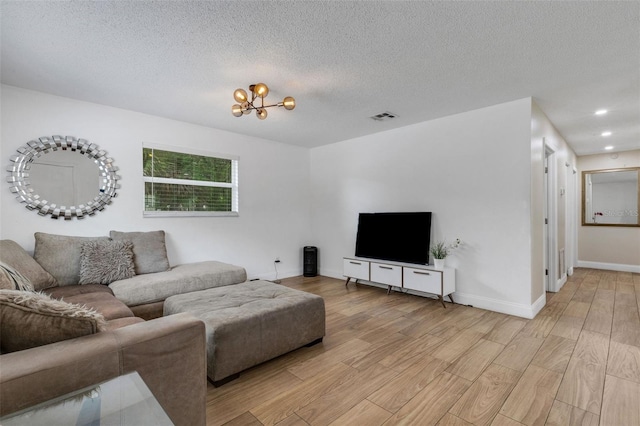 living room with a textured ceiling, a chandelier, and light hardwood / wood-style floors