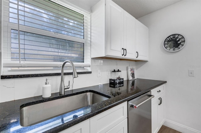 kitchen with dishwasher, a healthy amount of sunlight, dark stone countertops, and white cabinets