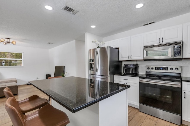 kitchen with a kitchen island, appliances with stainless steel finishes, light hardwood / wood-style floors, a breakfast bar, and white cabinets