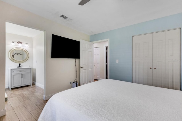 bedroom with a closet, ensuite bathroom, sink, ceiling fan, and light wood-type flooring