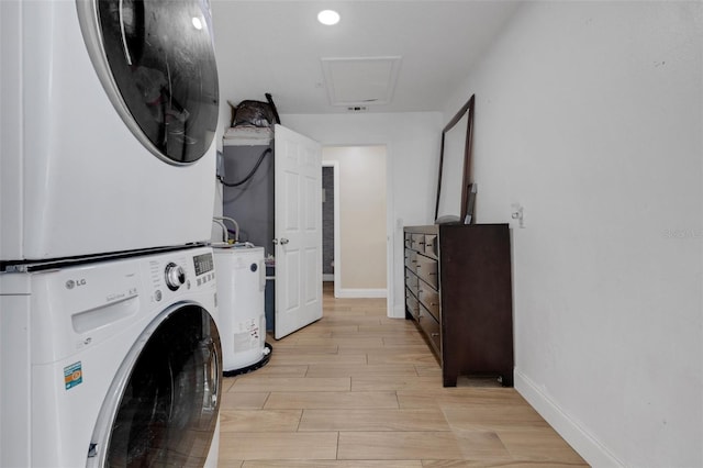 washroom with stacked washer and clothes dryer, light hardwood / wood-style floors, and electric water heater