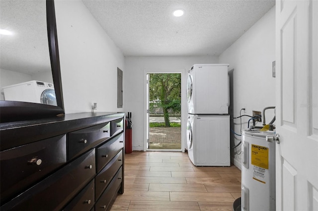 interior space featuring light wood-type flooring, stacked washer / dryer, a textured ceiling, and electric water heater