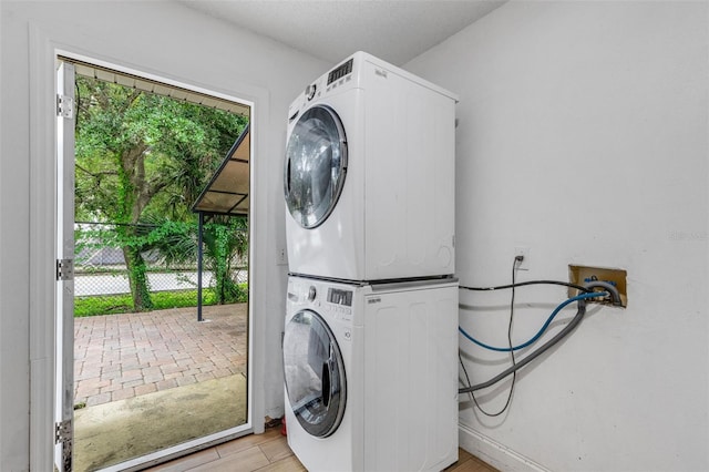 clothes washing area featuring light wood-type flooring and stacked washing maching and dryer