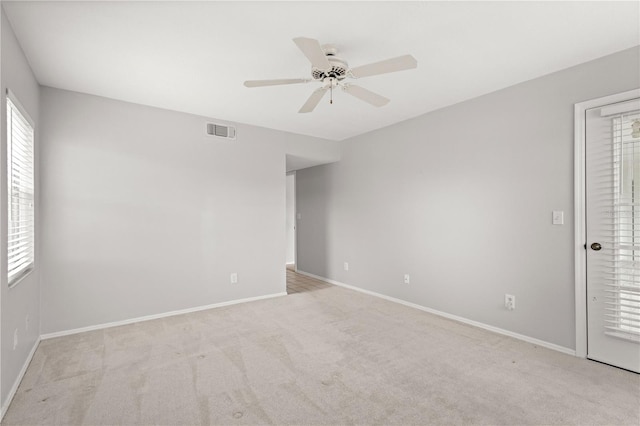 spare room with plenty of natural light, ceiling fan, and light colored carpet