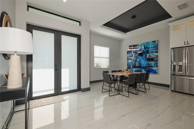 dining room featuring a tray ceiling and french doors